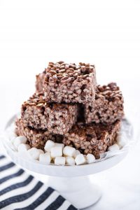 Gluten Free Chocolate Rice Krispie Treats stacked on a white cake stand garnished with mini marshmallows
