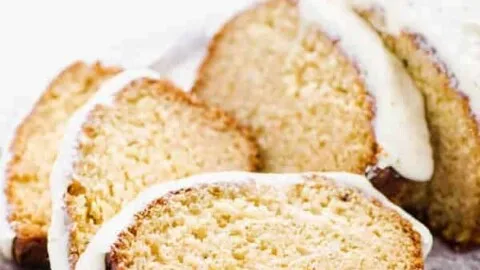Gluten Free Eggnog Bread with Eggnog Icing sliced on a wood platter lined with wax paper