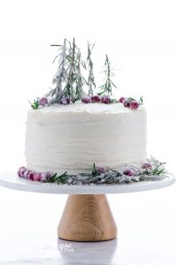 Gluten Free Gingerbread Cake on a cake stand decorated with sugared cranberries and sugared rosemary