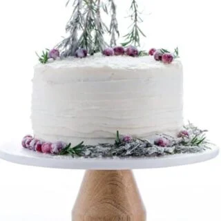 Gluten Free Gingerbread Cake on a cake stand decorated with sugared cranberries and sugared rosemary