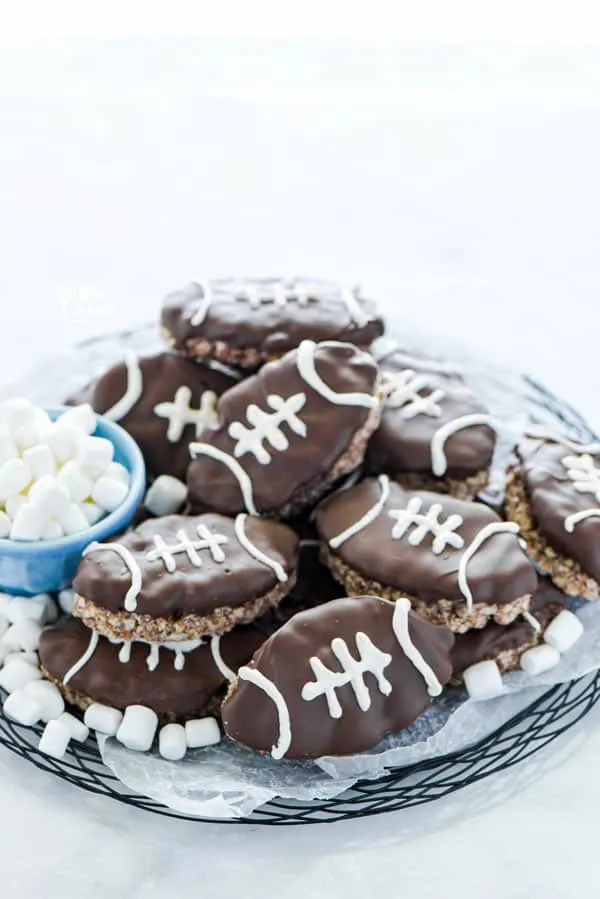 Football Rice Krispie Treats on a black wire platter garnished with mini marshmallows