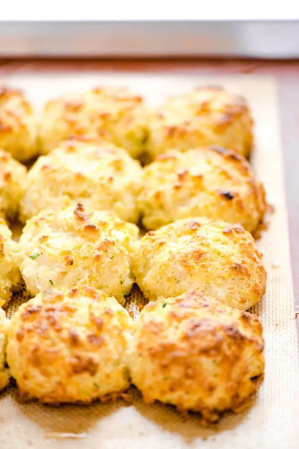 Gluten Free Cheddar Bay Biscuits on a Silpat lined half sheet pan