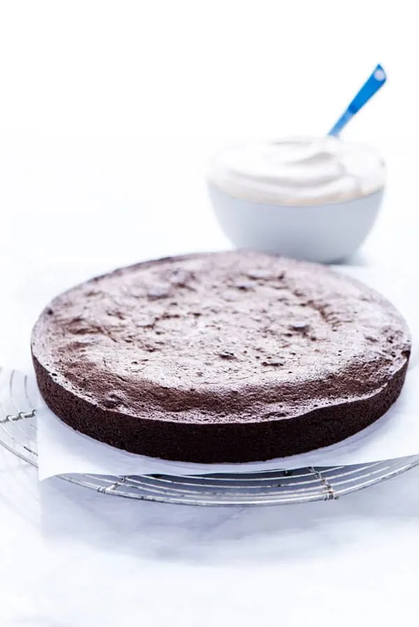 Flourless Chocolate Peanut Butter Cake on parchment paper and a round silver vintage cooling rack