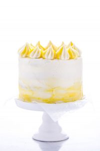Finished Gluten Free Lemon Cake recipe decorated with white and yellow frosting on a white cake stand