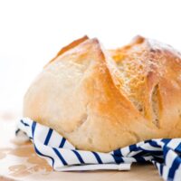 Gluten Free Sourdough Bread on a round wood cutting board with a blue and white striped napkin