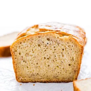 A loaf of Gluten Free Sourdough Banana Bread sliced on a piece of wax paper