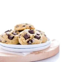 Gluten Free Sourdough Chocolate Chip Cookies on a small stack of white plates on top of a round wood cutting board