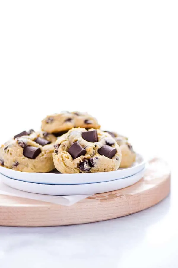 Gluten Free Sourdough Chocolate Chip Cookies on a small stack of white plates on top of a round wood cutting board