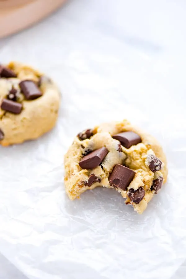 A gluten free sourdough chocolate chip cookie on top of parchment paper with a bite taken out