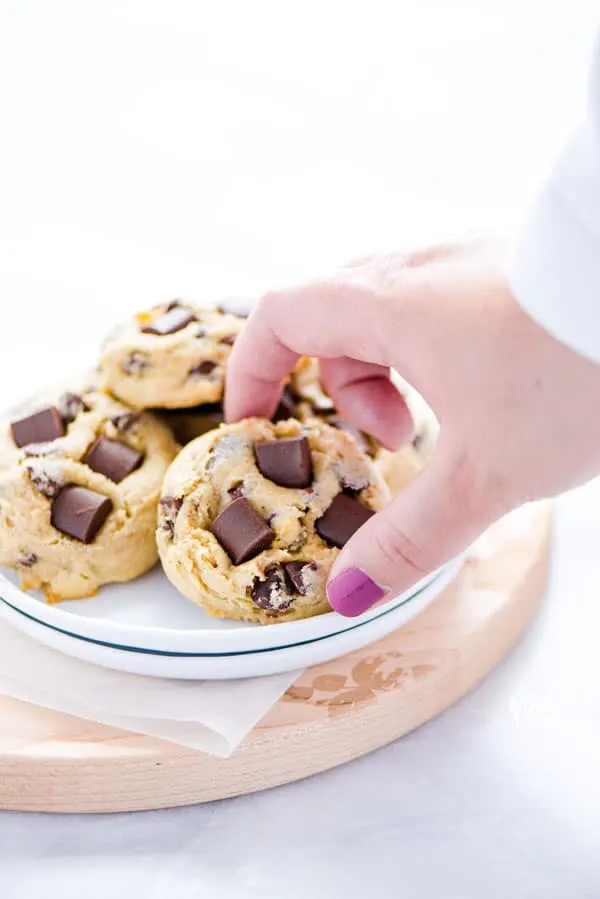 a hand reaching to pick up a gluten free sourdough chocolate chip cookie