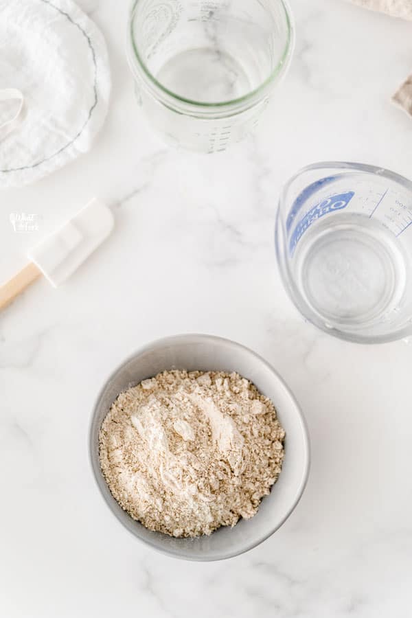 Top view of equipment needed for gluten free sourdough starter, spatular, measure cups, GF flour and mason jar.