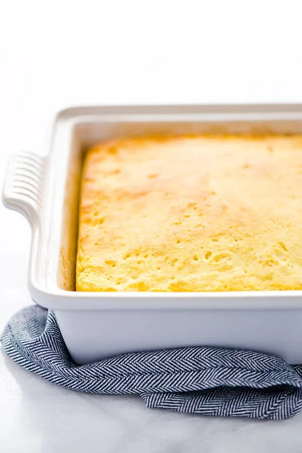 A fully baked gluten free sourdough cornbread recipe still in the pan on top of a blue towel