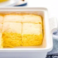 Baked and sliced gluten free sourdough cornbread recipe still in a gray stoneware pan on top of a blue kitchen towel