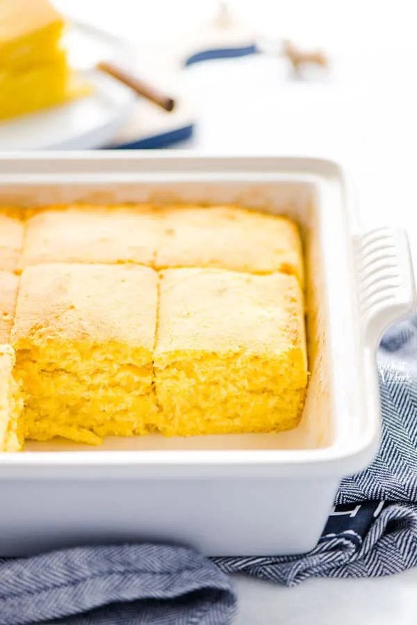 Baked and sliced gluten free sourdough cornbread recipe still in a gray stoneware pan on top of a blue kitchen towel