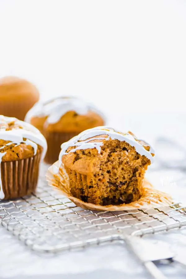 a gluten free sweet potato muffin with marshmallow glaze on top of a wire rack with a bite taken out