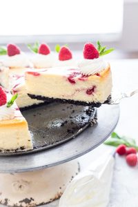 White chocolate raspberry cheesecake being served with one slice being lifted by a pie server