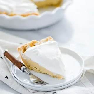 A slice of maple cream pie on a white plate with a wood trimmed fork