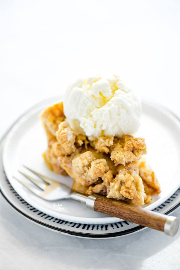 gluten free apple crisp pie on a plate topped with a scoop of vanilla ice cream