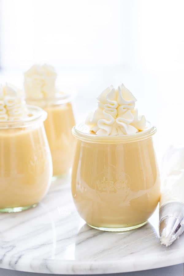 homemade maple pudding in individual Weck jars topped with whipped cream, ready to be served