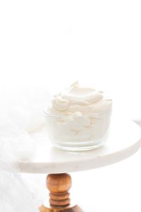 homemade whipped cream recipe in a glass bowl on top of a cake stand, ready to be served
