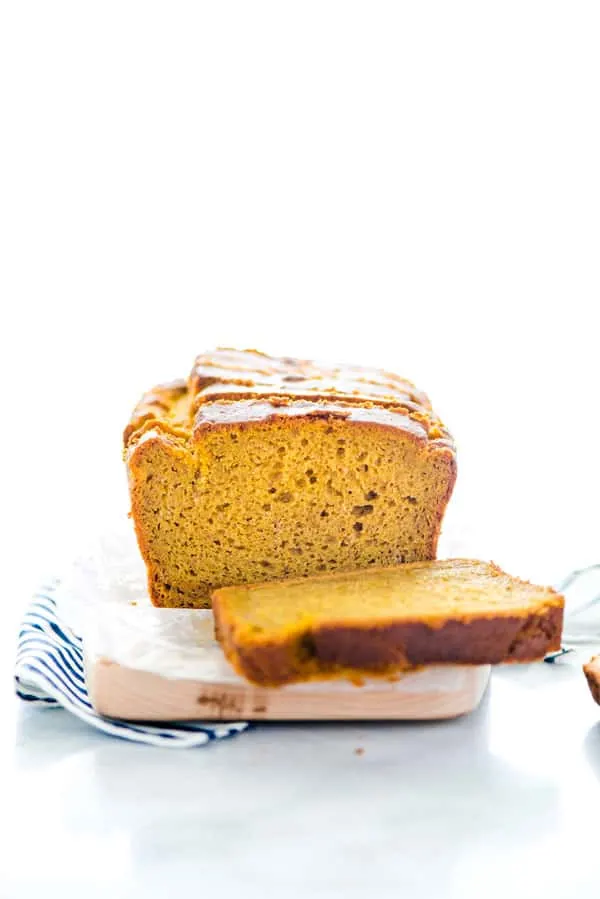 gluten free pumpkin spice bread that's been cut into to show the inside of the bread with one slice laying flat on the cutting board