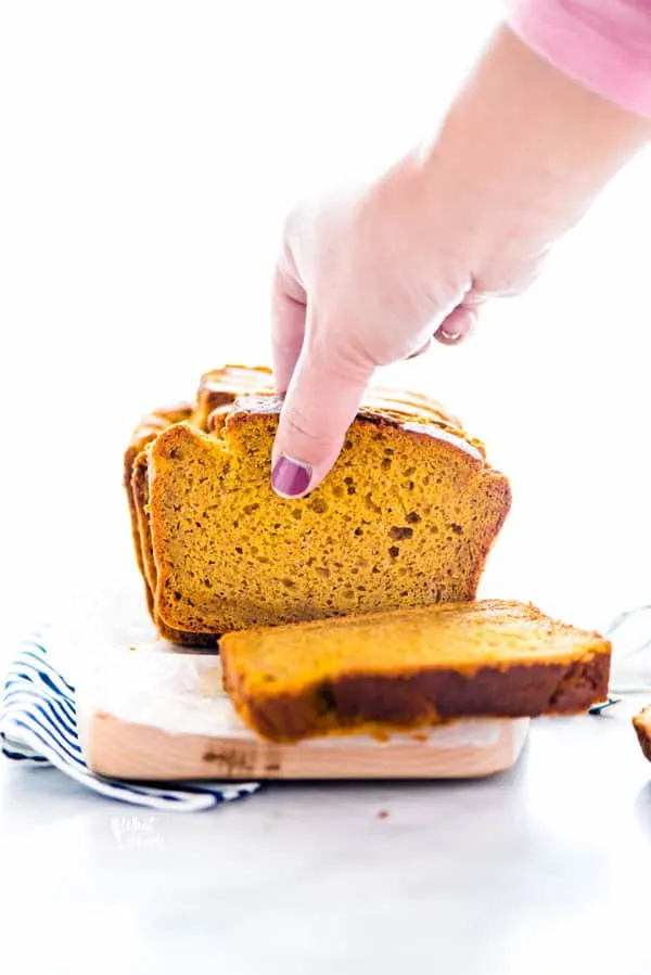 a hand grabbing a piece of gluten free pumpkin spice bread from above