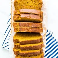 overhead shot of slice gluten free pumpkin spice bread on a narrow wood rectangular cutting board