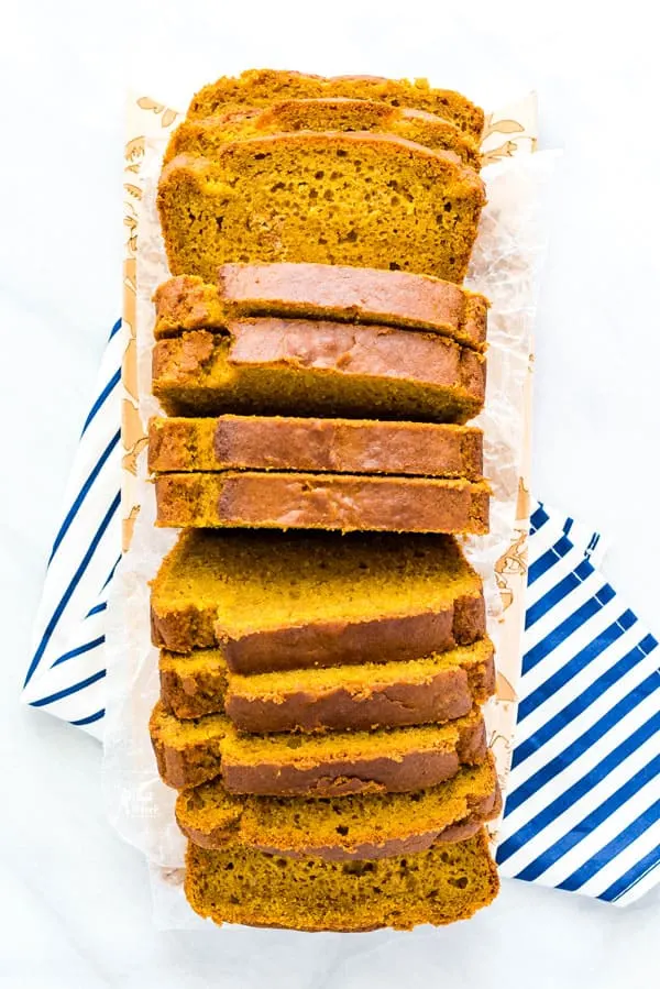 overhead shot of slice gluten free pumpkin spice bread on a narrow wood rectangular cutting board