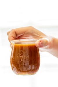 a hand holding homemade salted caramel sauce in a small Weck jar