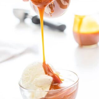 homemade salted caramel sauce being poured over a bowl of vanilla ice cream