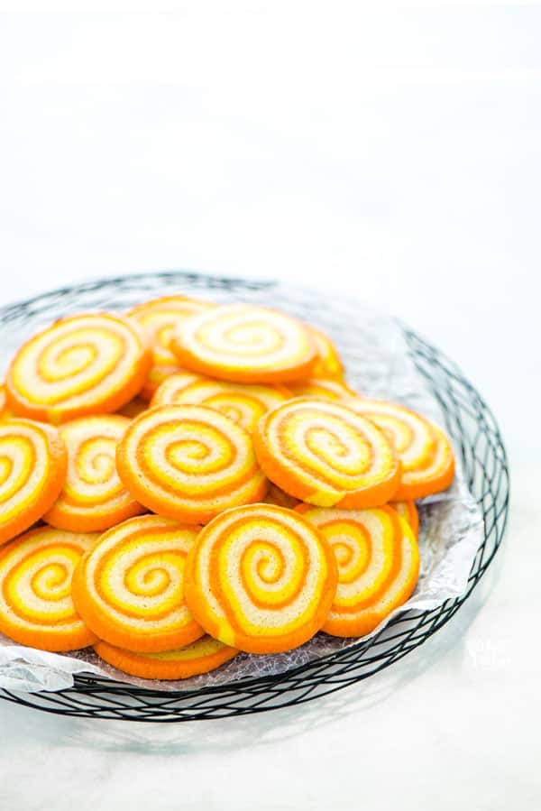 gluten free candy corn pinwheel cookies on a black wire platter lined with wax paper