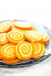 Gluten Free Candy Corn Pinwheel Cookies on a black wire platter lined with wax paper