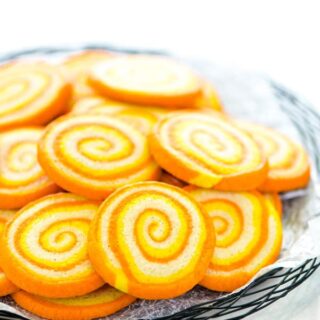 Gluten Free Candy Corn Pinwheel Cookies on a black wire platter lined with wax paper