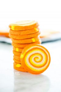 a stack of gluten free candy corn pinwheel cookies on a marble surface