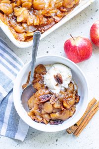 cinnamon baked apple slices being served in a bowl with vanilla ice cream