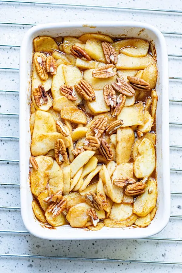 cinnamon baked apple slices in a white casserole dish ready to be baked