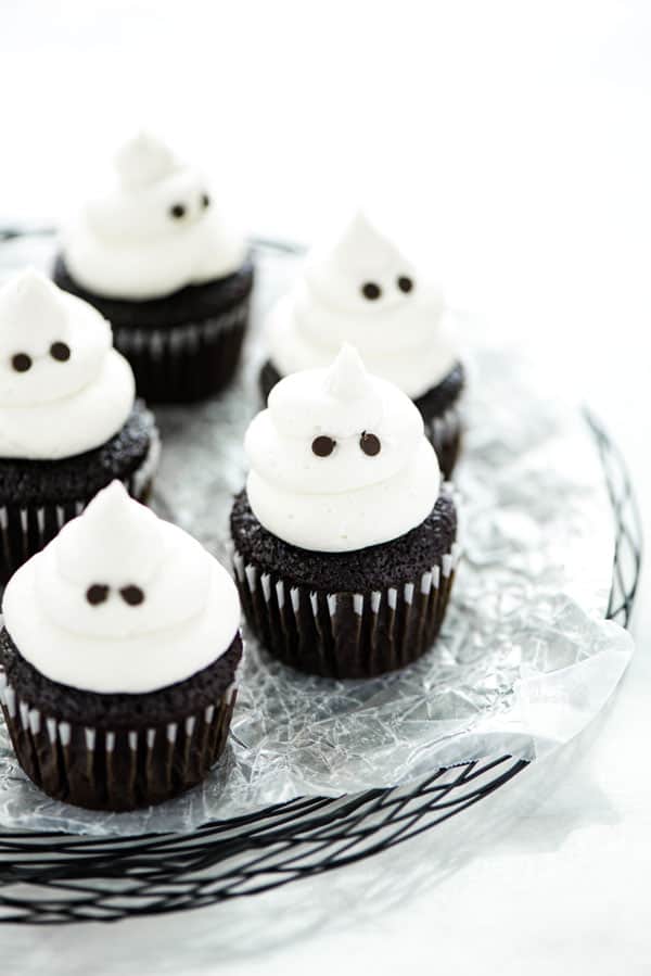 gluten free ghost cupcakes are made with chocolate cupcakes topped with white buttercream frosting and mini chocolate chips for eyes