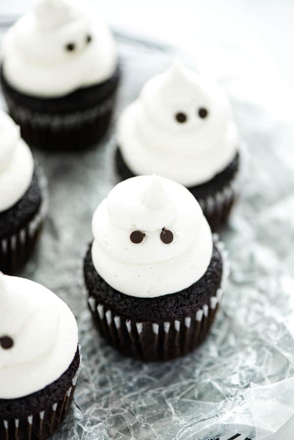 Gluten Free Halloween Ghost Cupcakes on a black wire plater lined with crinkled wax paper