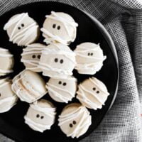 Mummy Macarons with Maple Cinnamon Filling on a black plate over a black and white napkin