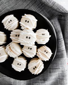 Mummy Macarons with Maple Cinnamon Filling on a black plate over a black and white napkin