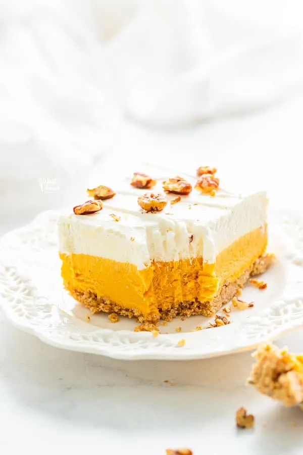a pice of gluten free pumpkin lush cake on a white plate with a forkful removed