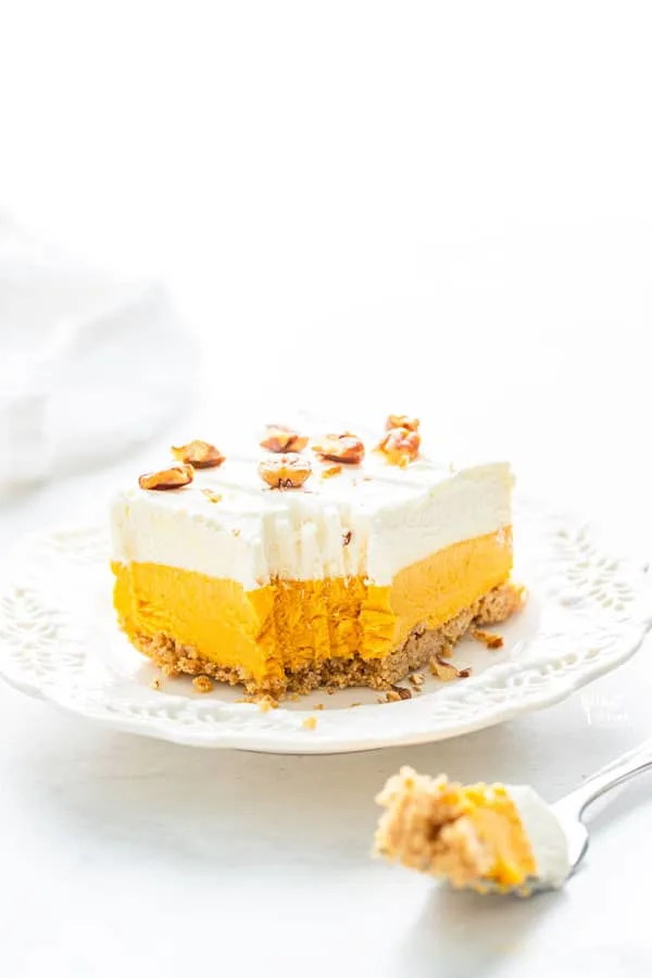 a pice of gluten free pumpkin lush cake on a white plate with a forkful removed