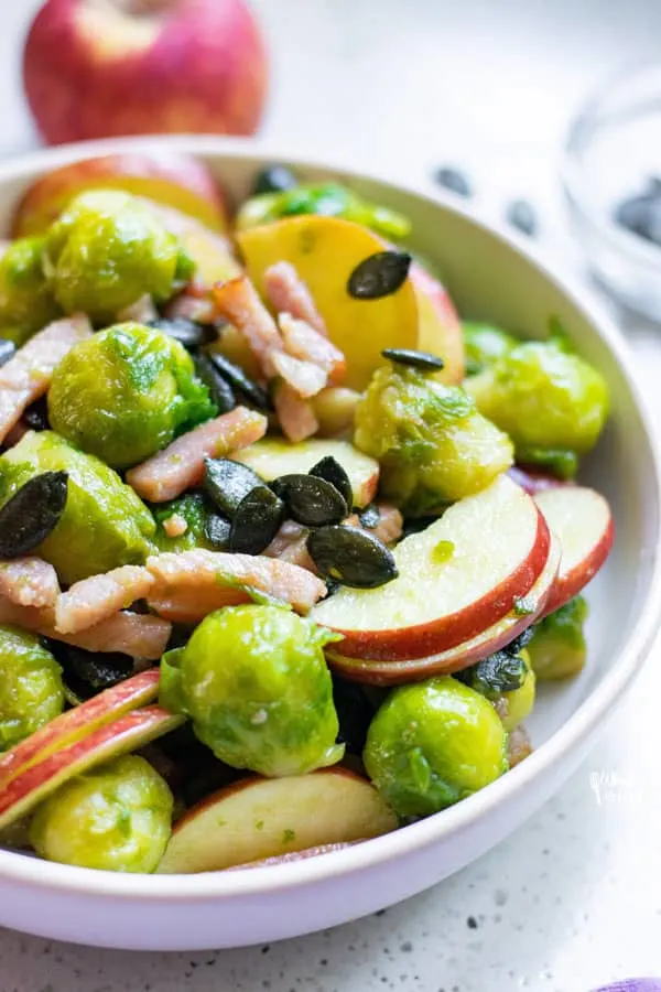 Sautéed Brussels Sprouts with Bacon and Apple in a white serving bowl