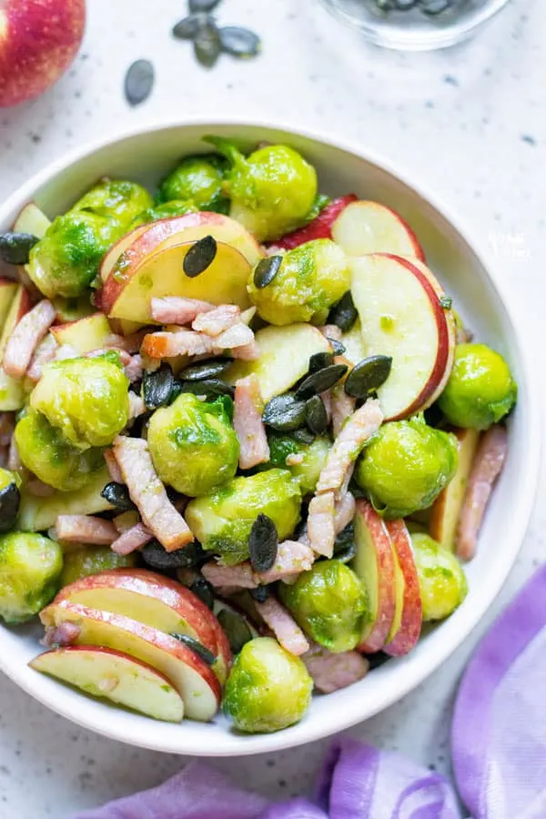 overhead shot of Sautéed Brussels Sprouts with Bacon and Apple in a white serving bowl