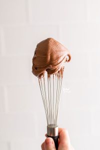 a dollop of chocolate cream cheese frosting on the tip of a wire whisk