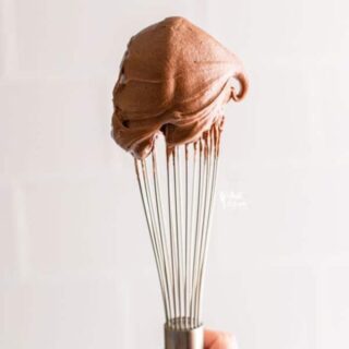 a dollop of chocolate cream cheese frosting on the tip of a wire whisk