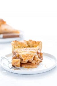 a slice of gluten free apple pie on a small white plate with a bite taken out