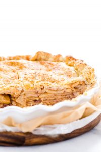 Straight on shot of a gluten free apple pie that's been sliced into showing the layers of apples in the flaky crust