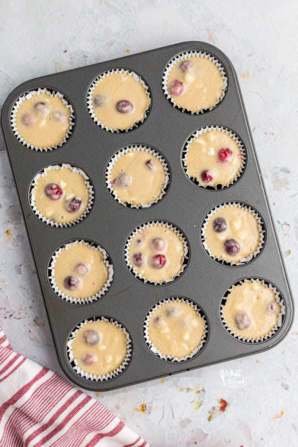 batter for gluten free white chocolate cranberry muffins in a muffin tin lined with paper liners ready to be baked