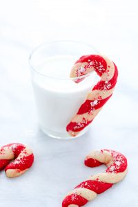 a gluten free candy cane cookie hanging on a glass of milk